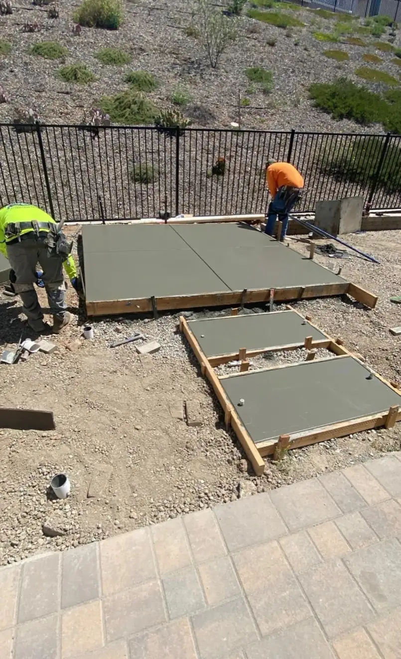 Crew leveling wet concrete for a new backyard patio